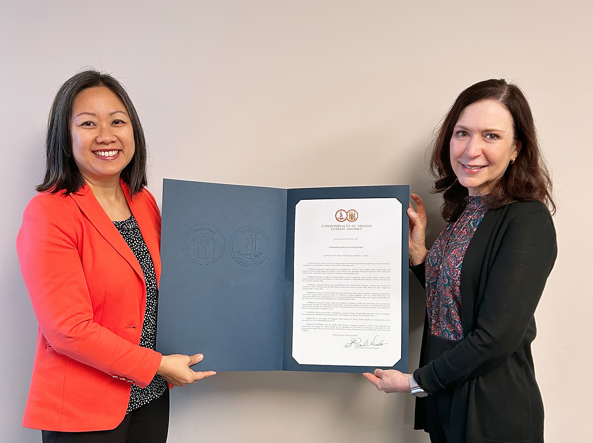 Delegate Kathy Tran, of the Virginia House of Delegates, smiles at the camera while holding a physical copy of the commendation for Acting For Young People (AFYP). Mary Lechter, Founder of AFYP and Executive Director for Mason Community Arts Academy holds up the opposite side of the commendation.