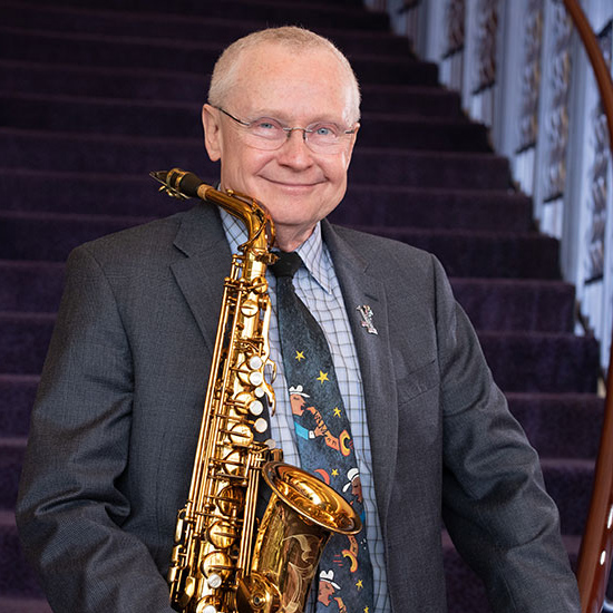 Prof. Jim Carroll holding his saxophone wearing a snazzy tie