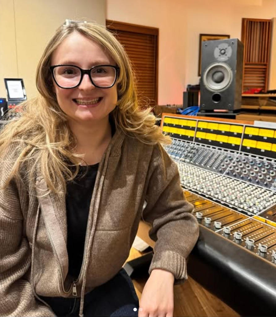 Mara Keen music alum and composer sitting in front of her electronic mixing equipment