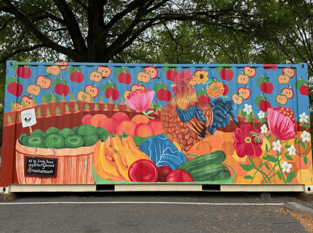 Mural painted on a container depicting fruits and vegetables, flowers and apples, a cockrel and apples in the sky