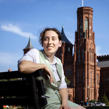 Stephanie Aitken sitting on a bench in front of the Smithsonian Castle in DC